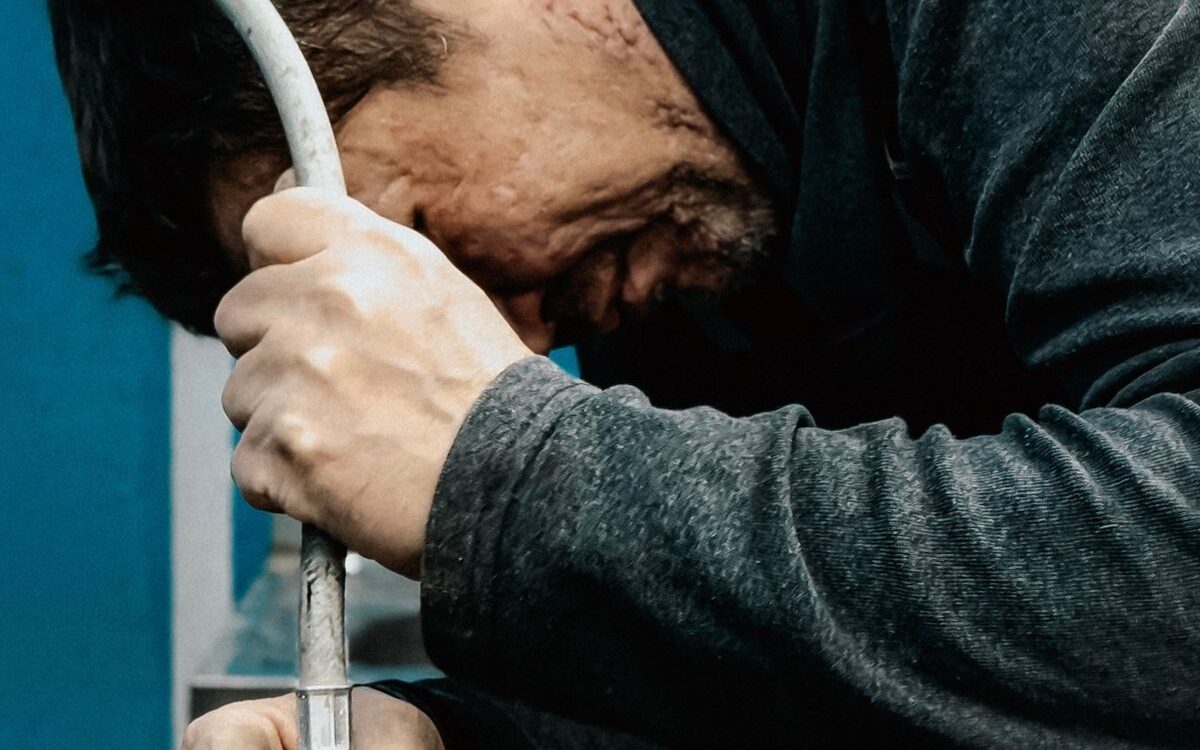 Plumber repairing pipework under a sink, the kind of job that affects plumbing costs in Victoria