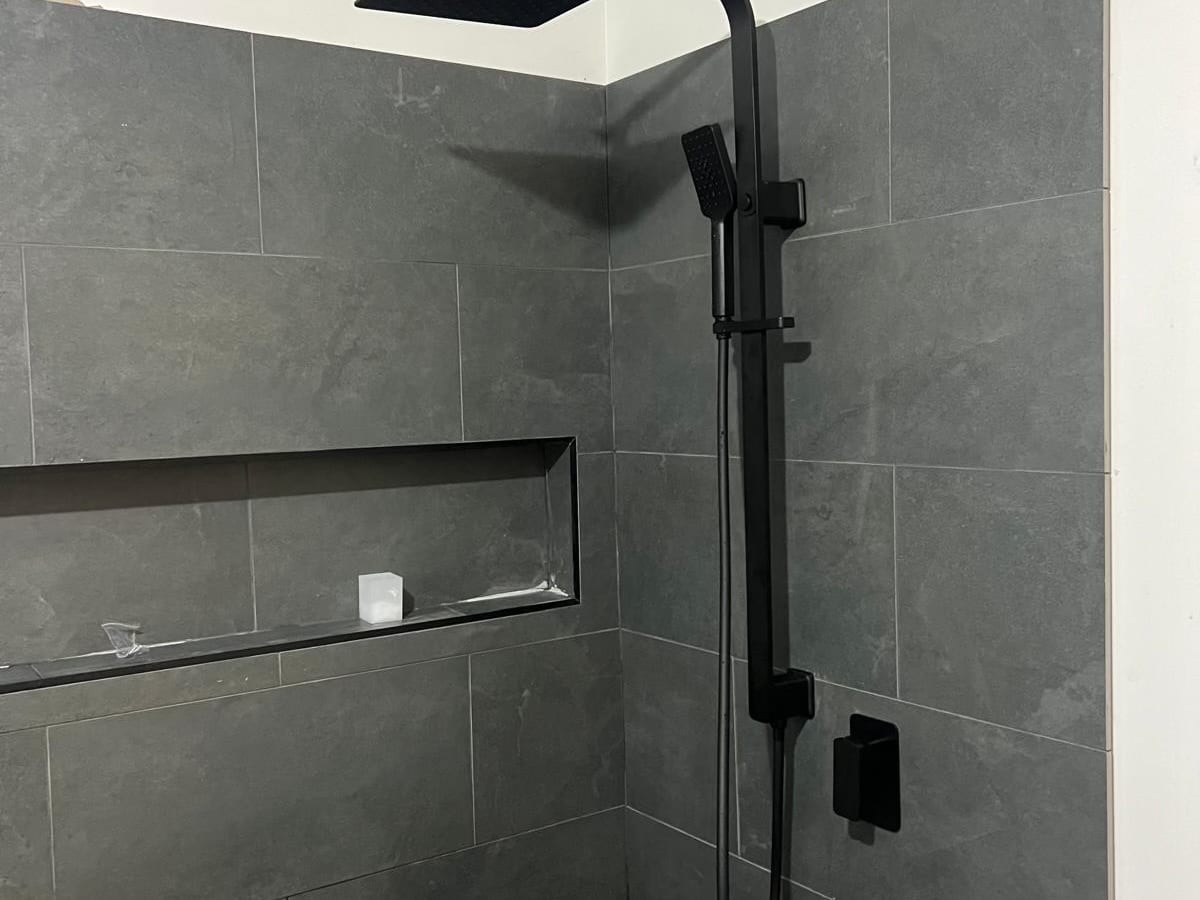 Shower with black fittings and a tiled niche