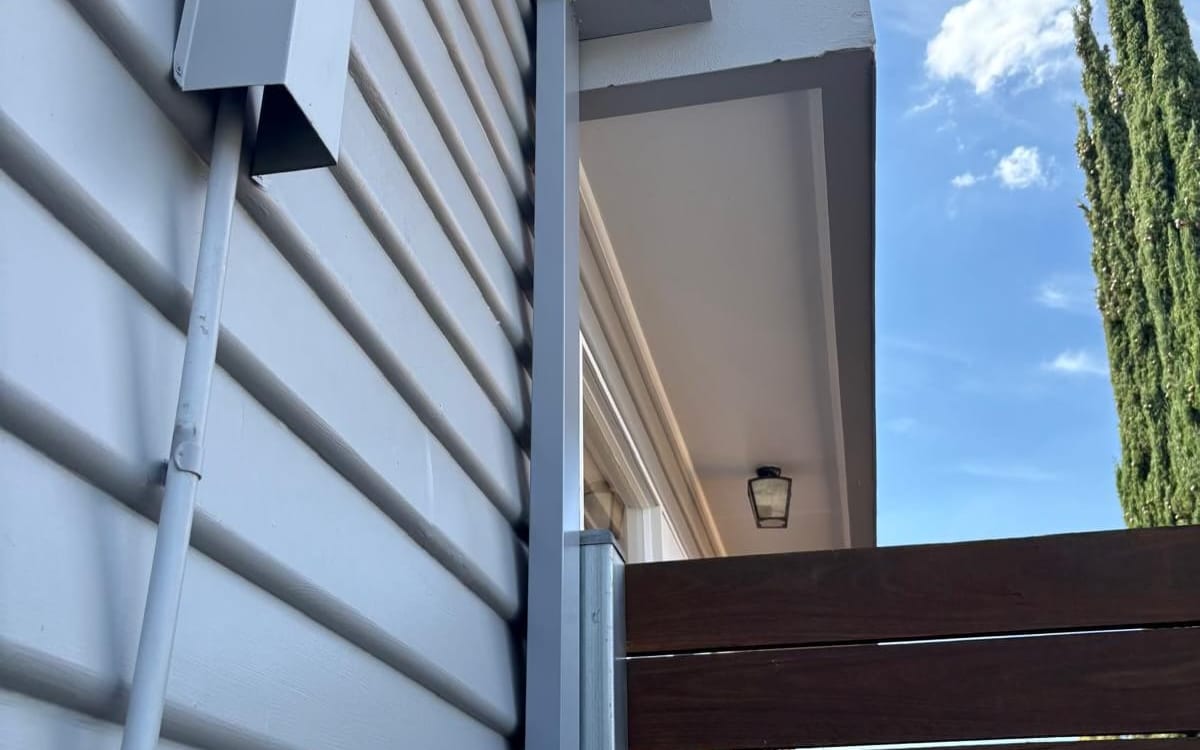 Downpipe and gas meter on a weatherboard wall
