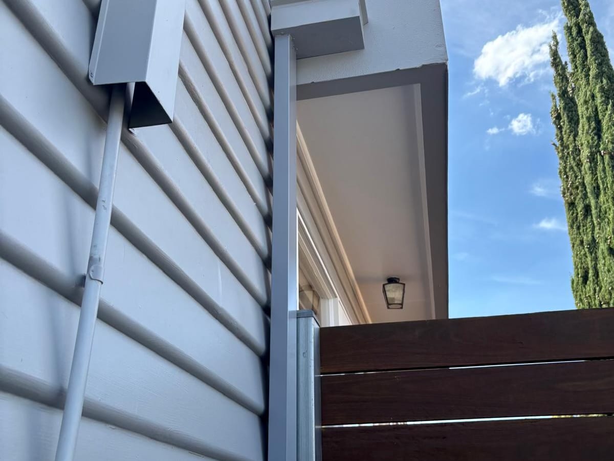 Downpipe and gas meter on a weatherboard wall