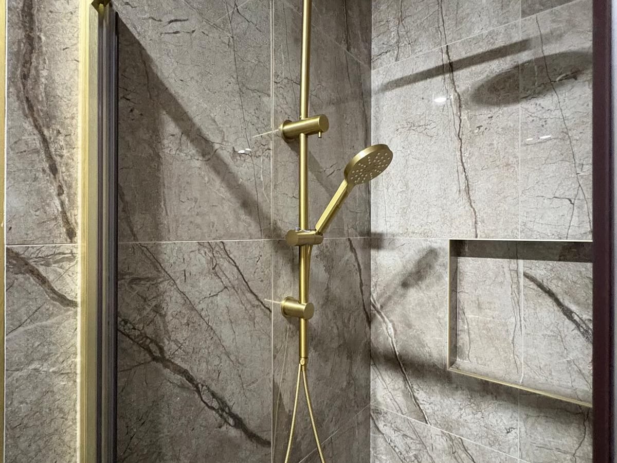 Brass shower mixer and rail in a tiled shower