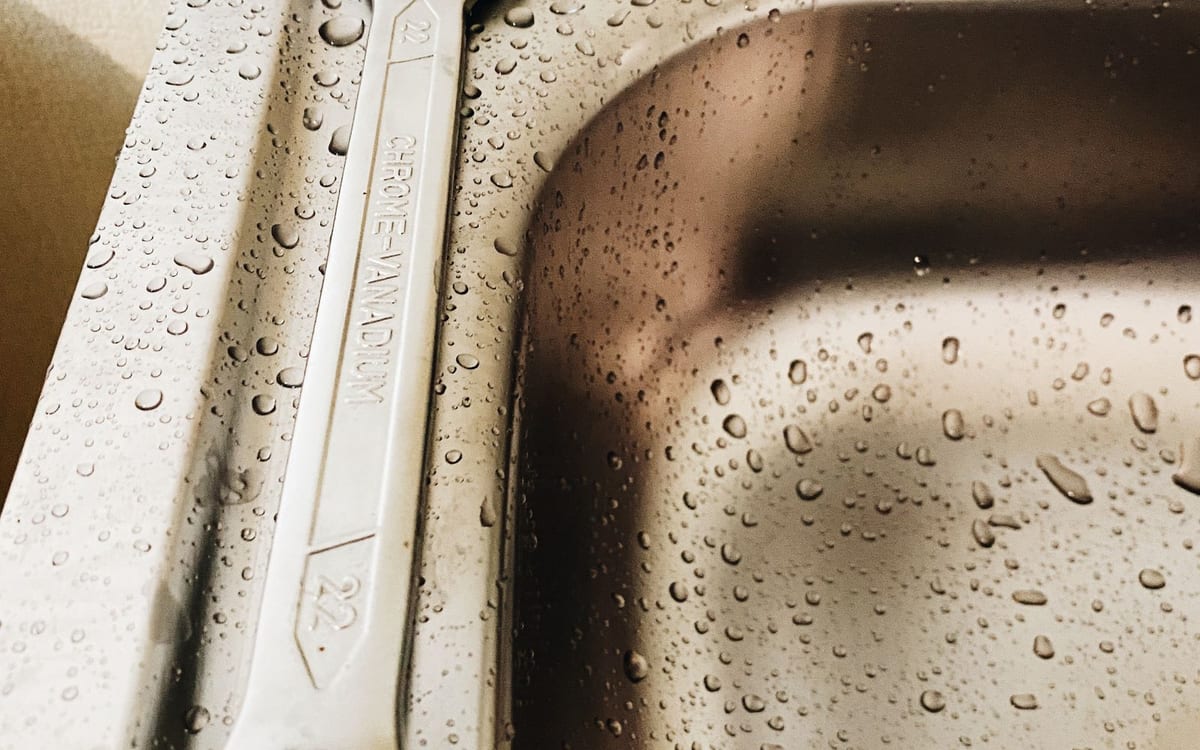 Wrench resting on a wet stainless sink